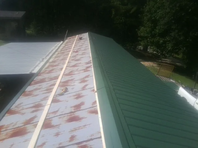 Old rusted panels beside newly installed green metal roofing — Wind Damage Roof Repair by Roofing Brothers in Potomac