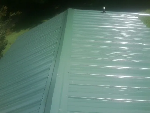 New green metal panels meeting at the ridge of a roof — Flat Roof Repair work by our crew in Potomac