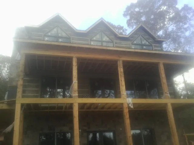 Dormers and porch framing on a large log home under construction — Roof Coating work by our crew in Potomac