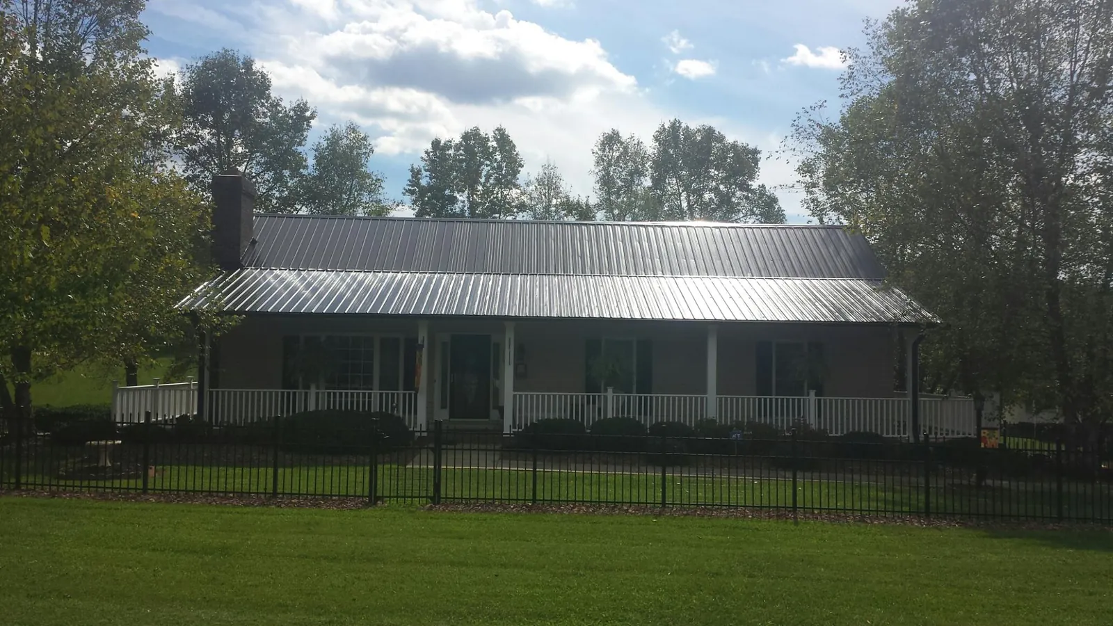 Gray metal roof on a brick ranch with a full width front porch — Gutter Guard Installation work by our crew in Potomac