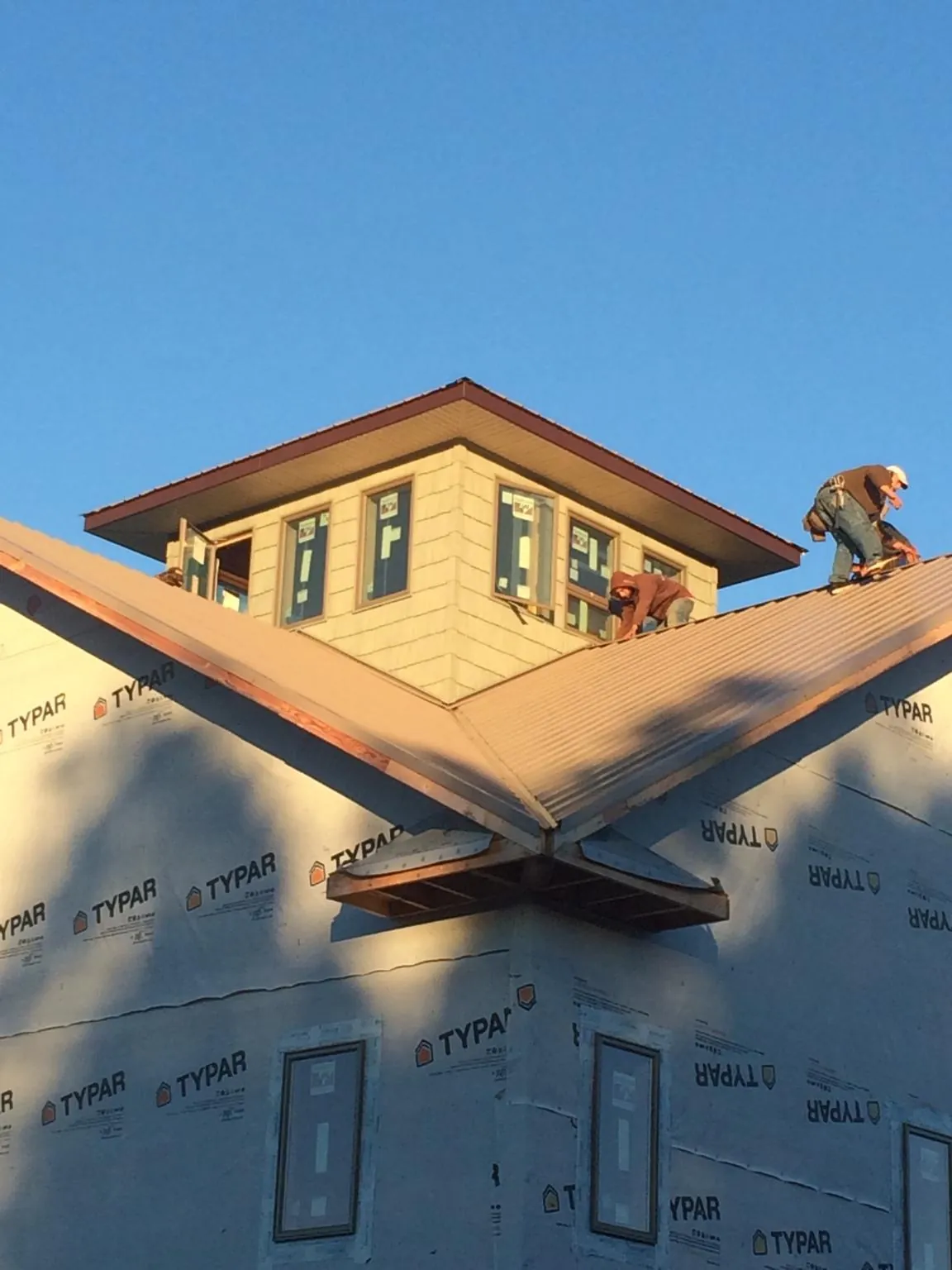 Roofers working around a rooftop cupola on a new metal roof at sunset — Roof Waterproofing in Potomac by Roofing Brothers